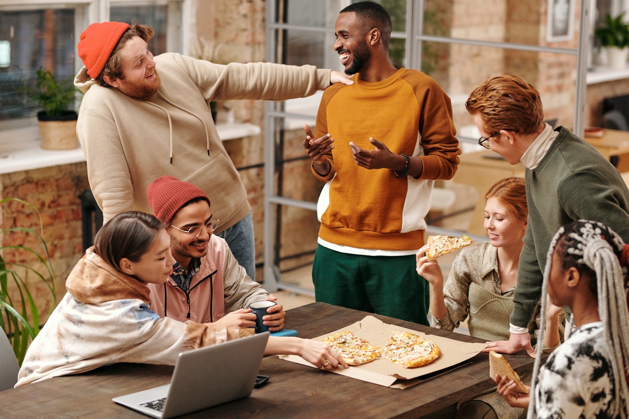 people talking and enjoying pizza outside